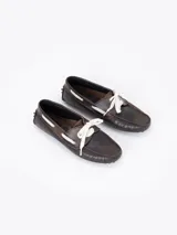 Mocasín de cuero vacuno con efecto gastado, diseño de la colaboración Jazmín Chebar x Guido. Presenta detalles de picado en laterales y capellada, con cordones blancos y suela de goma con relieve.