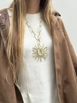 Collar largo de bronce con cadena de eslabones ovalados y un gran dije colgante con diseño de sol.