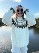 Sweater tejido a mano en lana merino color crudo con diseño geométrico en marrón y cuello alto.