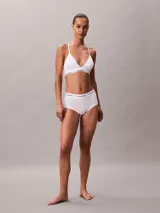 Bralette de triángulo Calvin Klein, confeccionado en una mezcla de algodón y modal. Presenta copas ligeramente forradas, tirantes ajustables y la icónica banda elástica con el logo de la marca. Diseño sin aros para mayor comodidad.