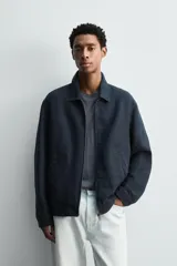 Cazadora regular fit color azul marino, confeccionada en tejido de lino con efecto ligeramente lavado. Presenta cuello solapa, manga larga con puño abotonado, bolsillos de vivo en la cadera y un bolsillo interior. Cierre frontal con cremallera.