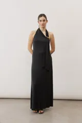 Vestido largo negro de corte al cuerpo con cuello halter y detalle de hebilla metálica dorada en el hombro con tira drapeada.