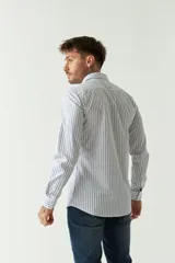 Camisa de hombre de corte slim fit, confeccionada en algodón con diseño de rayas verticales finas en tonos claros. Presenta cuello clásico, cierre frontal con botones y logo bordado en el pecho.