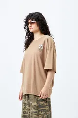 Remera negra de corte holgado con mangas cortas amplias y cuello redondo. Estampado pequeño de flor en el pecho y estampado grande en la espalda con diseño floral y texto.