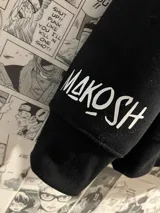 Campera negra con capucha y cierre frontal, con estampado en la espalda de texto en japonés en color blanco. Diseño inspirado en el anime Haikyu!!