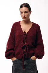 Saco tejido de punto color azul, con escote en V y cierre frontal mediante lazos. Presenta mangas largas amplias con puños ajustados y un calce relajado.