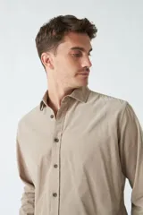 Camisa de pana color beige, de corte regular, con cuello clásico y cierre frontal con botones. Confeccionada en algodón.