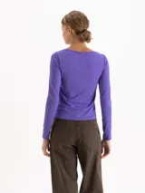 Top de manga larga color violeta, con escote en V y detalle de fruncido central regulable mediante lazos finos en el delantero. Presenta un ajuste entallado al cuerpo.