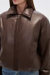 Campera estilo bomber de eco-cuero negra, con cuello camisero, cierre frontal y puños y cintura ajustados con elástico.