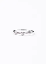 Anillo de plata 925 con un punto de luz central redondo engastado en bisel, flanqueado por una hilera de zirconias pequeñas engastadas a lo largo del cuerpo del anillo.