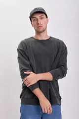 Buzo de cuello redondo en color negro con efecto lavado, de corte holgado y mangas largas con puños acanalados.