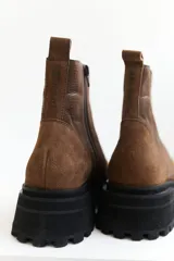 Bota corta de cuero color marrón con suela track negra y cierre lateral con cremallera.