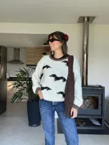 Buzo de punto tejido a mano en lana merino, color blanco marfil con detalles en marrón en el cuello y los puños, y un estampado de perros salchicha distribuidos por la prenda.