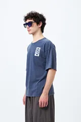 Remera negra de corte amplio con mangas cortas y cuello redondo. Presenta un pequeño estampado rectangular en el pecho y un estampado grande en la espalda con motivos japoneses.