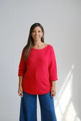 Sweter de punto color rojo, con escote a la base y mangas largas con puños doblados. Presenta un corte holgado y diseño básico.