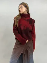 Buzo de lana merino afieltrada con diseño artesanal de efecto degradado en tonos violeta y fucsia. Presenta cuello alto, hombreras marcadas y corte holgado.