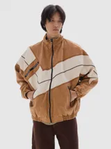Campera de denim estilo deportivo con diseño de paneles en tonos azul claro y blanco, cuello alto, cierre frontal y bolsillos laterales con cierre. Presenta corte oversized con puños y cintura elásticos.