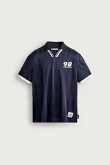 Polo relaxed fit de tejido técnico, con diseño a rayas verticales en tonos azul marino y negro. Cuenta con cuello polo y escote en V con ribete blanco y negro, mangas cortas con puños blancos y estampa frontal alusiva a Francia 98 con aplique de etiquetas oficiales.
