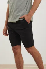 Bermuda de gabardina en color verde claro, con corte recto, bolsillos laterales y cierre frontal con botón y cremallera.