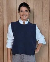 Chaleco de punto tejido en lana lambswool, con cuello redondo, diseño sin mangas y aberturas laterales con botones. Presenta una textura acanalada y un corte holgado.