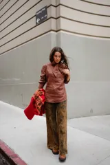Blusa de lino color marrón con cuello tipo lazo, mangas largas y diseño entallado con pinzas frontales.