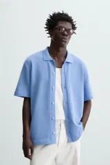 Cárdigan celeste de tejido de algodón con estructura tipo waffle. Tiene cuello solapa, manga corta y cierre frontal con botones.