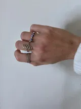 Anillo de acero quirúrgico con diseño de ojos turcos intercalados con pequeñas piedras brillantes.
