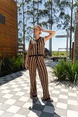 Pantalón tejido de corte recto y tiro alto, con diseño de rayas verticales onduladas en colores beige y negro. Presenta una cintura elástica con cordón ajustable.