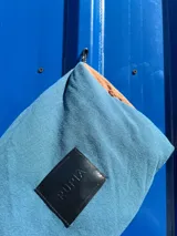 Necessaire azul y marrón con grifa de goma, detalles de cordón, cierre y bolsillo transparente interior.