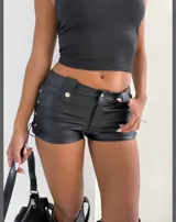 Short negro de cuero sintético con cintura alta, cierre frontal con botón y cordones cruzados en los laterales.