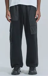 Pantalón tipo jogger de corte holgado, color negro, con bolsillos laterales tipo cargo en material de microfibra y base de algodón. Cuenta con cintura elástica y botamanga regulable.