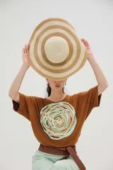 Remera color marrón con aplique textil en forma de espiral con cintas de colores pastel.