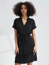 Vestido corto con estampado animal print tipo cebra en tonos blanco y negro. Presenta escote en V, mangas cortas y un lazo ajustable en la cintura para entallar la silueta.