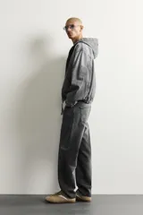 Pantalón de jean corte slim fit con efecto lavado, tiro medio, cinco bolsillos y cierre frontal con cremallera y botón.