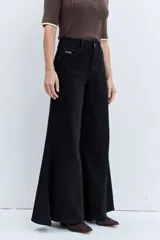Jeans de tiro alto en color negro, con diseño de corte acampanado y paneles godet que aportan amplitud en el bajo. Presenta costuras visibles y cierre frontal con botón y cremallera.