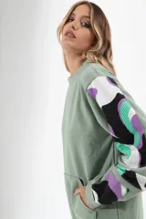 Buzo blanco de corte holgado con cuello redondo y mangas largas con estampado abstracto en negro.