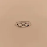Anillo de plata 925 con diseño de infinito, una de las curvas está engastada con circonias.