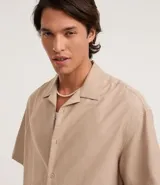 Camisa de manga corta color negro, con diseño boxy, cuello clásico y abotonado frontal.