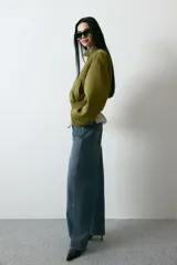 Jean de tiro alto y corte baggy, confeccionado en denim de algodón rígido en tono azul medio con efecto deslavado. Presenta diseño de cinco bolsillos, trabillas para cinto y cierre frontal con botón y cremallera.