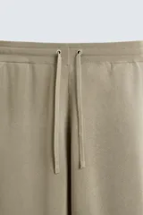 Bermuda de punto color beige claro, corte relajado, con cintura elástica ajustable mediante cordón y bolsillos laterales.