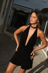Vestido corto negro de punto con escote halter muy pronunciado en V y falda con vuelo.