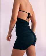 Minivestido fucsia con escote halter cruzado, espalda descubierta y falda ajustada con frunces.