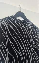 Top negro de mangas largas con estampado de líneas plateadas.