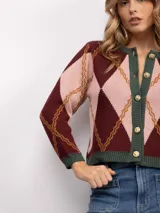 Cardigan de punto con patrón argyle en tonos azul marino, celeste y naranja. Presenta cuello redondo, cierre frontal con botones dorados y terminaciones en tejido acanalado gris.