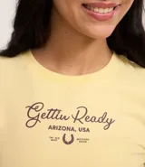 Remera corta color amarillo pastel, de algodón, con cuello redondo y mangas cortas. Estampado frontal con la frase "Gettin Ready Arizona, USA" y un herraje.