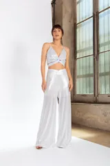 Pantalón de tiro alto confeccionado en tela de lamé brillante, con corte amplio y fluido tipo palazzo.