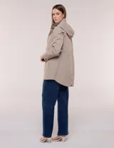 Campera impermeable Gallery de color beige, con capucha plegable, cierre frontal oculto con botones a presión, bolsillos delanteros y cordón de ajuste en la cintura.