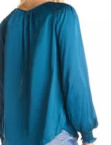 Blusa de satén color verde azulado con acabado sedoso y fluido. Escote a la base con frunce perimetral, mangas largas estilo balloon con detalle de punto smock en hombros y puños. Espalda con abertura tipo gota y botón forrado a tono.