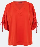 Blusa amplia color naranja, con escote en pico y mangas cortas con detalle de lazo fruncido.