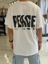 Remera oversize blanca de manga corta, con gran estampado negro en la espalda con la palabra 'Peace' y símbolos gráficos.